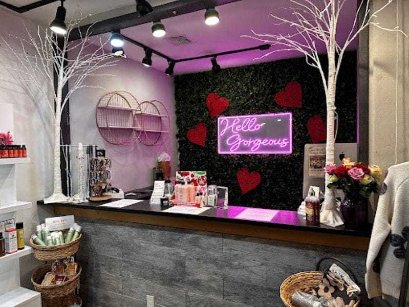 Luxurious beauty salon reception with neon "Hello Gorgeous" sign and elegant decor.