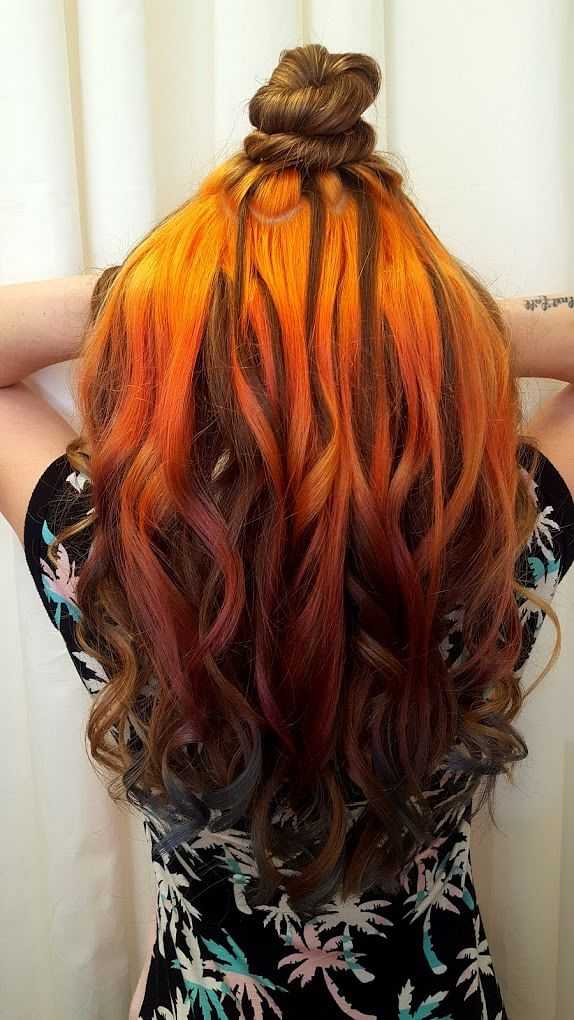 Client's softly curled hair falling down her back showing the dimension from dark brown underneath to golden orange babylights on top